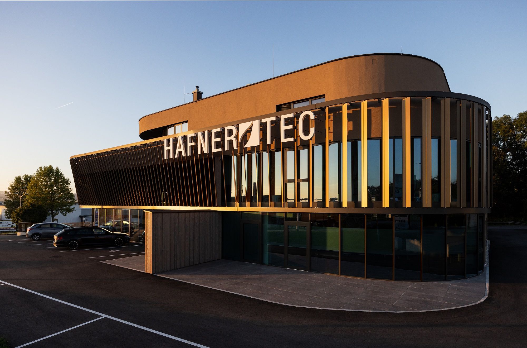 Modernes Gebäude mit der Aufschrift 'HAFNER TEC' bei Sonnenuntergang.