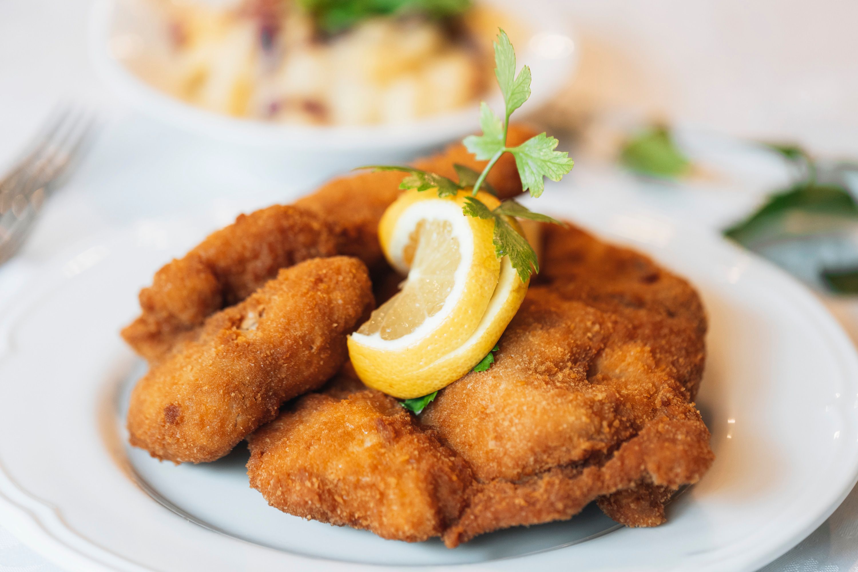 Gebackenes Hähnchen mit Zitronenscheibe und Petersilie auf einem Teller.