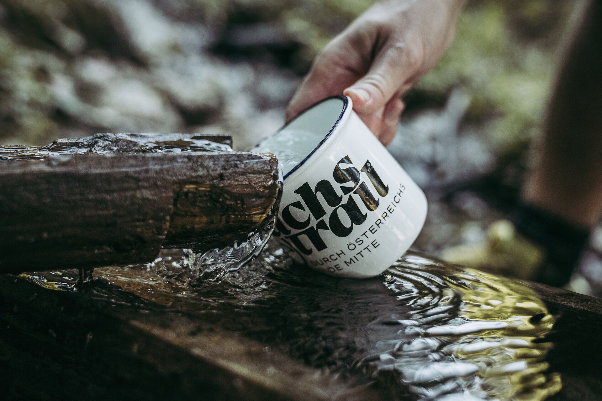 Eine erfrischende Trinkpause am glitzernden Wasser, während die sanften Klänge der Natur um einen herum erklingen. Die Emailletasse in der Hand spiegelt die Schönheit der Umgebung wider, während die Ybbstaler Alpen majestätisch im Hintergrund thronen. Hier wird jeder Schluck zum Genuss und jede Sekunde zur Erinnerung.