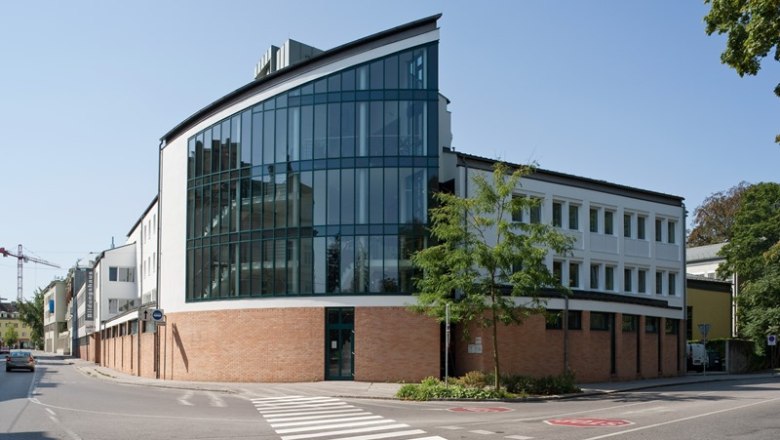 Modernes Geb&auml;ude mit Glasfassade und Ziegelmauerwerk an einer Stra&szlig;enecke.