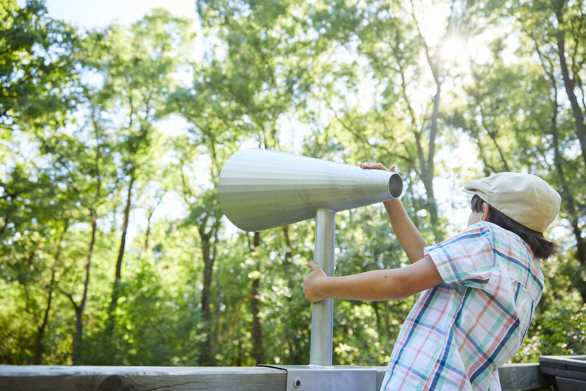 Ein Kind blickt neugierig durch ein Fernrohr und entdeckt die Schönheit der Natur. Umgeben von üppigem Grün und dem sanften Licht der Sonne, wird die Freude am Entdecken und Erforschen lebendig. Diese friedliche Atmosphäre lädt Familien ein, die Wunder der Umgebung gemeinsam zu erleben.