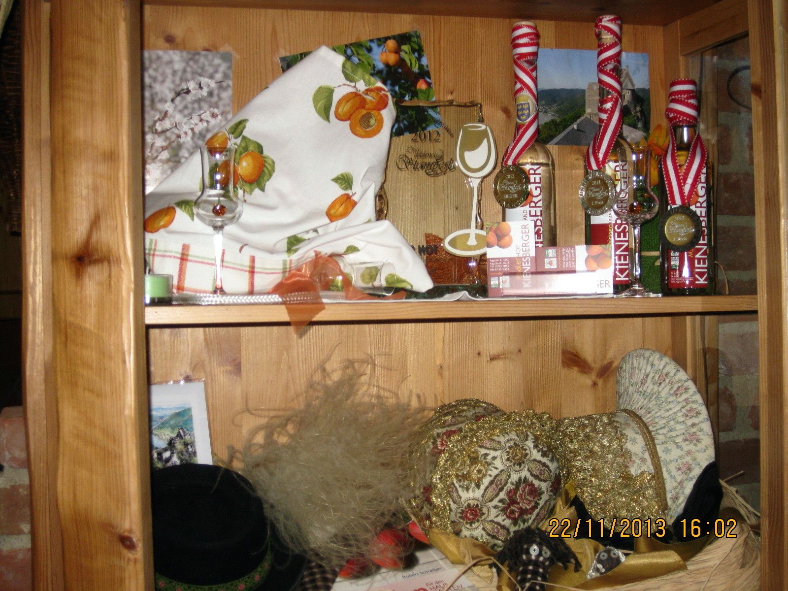 Holzregal mit Dekorationen, Likörflaschen und Hüten.