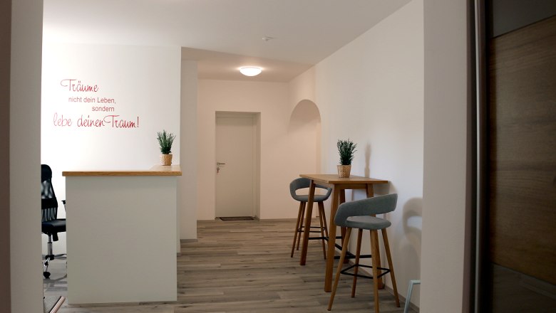 Moderner Innenraum mit Barhockern und Pflanzen auf einem Tisch.