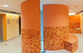 Interior view of a wellness area with orange mosaic tiles and round walls.