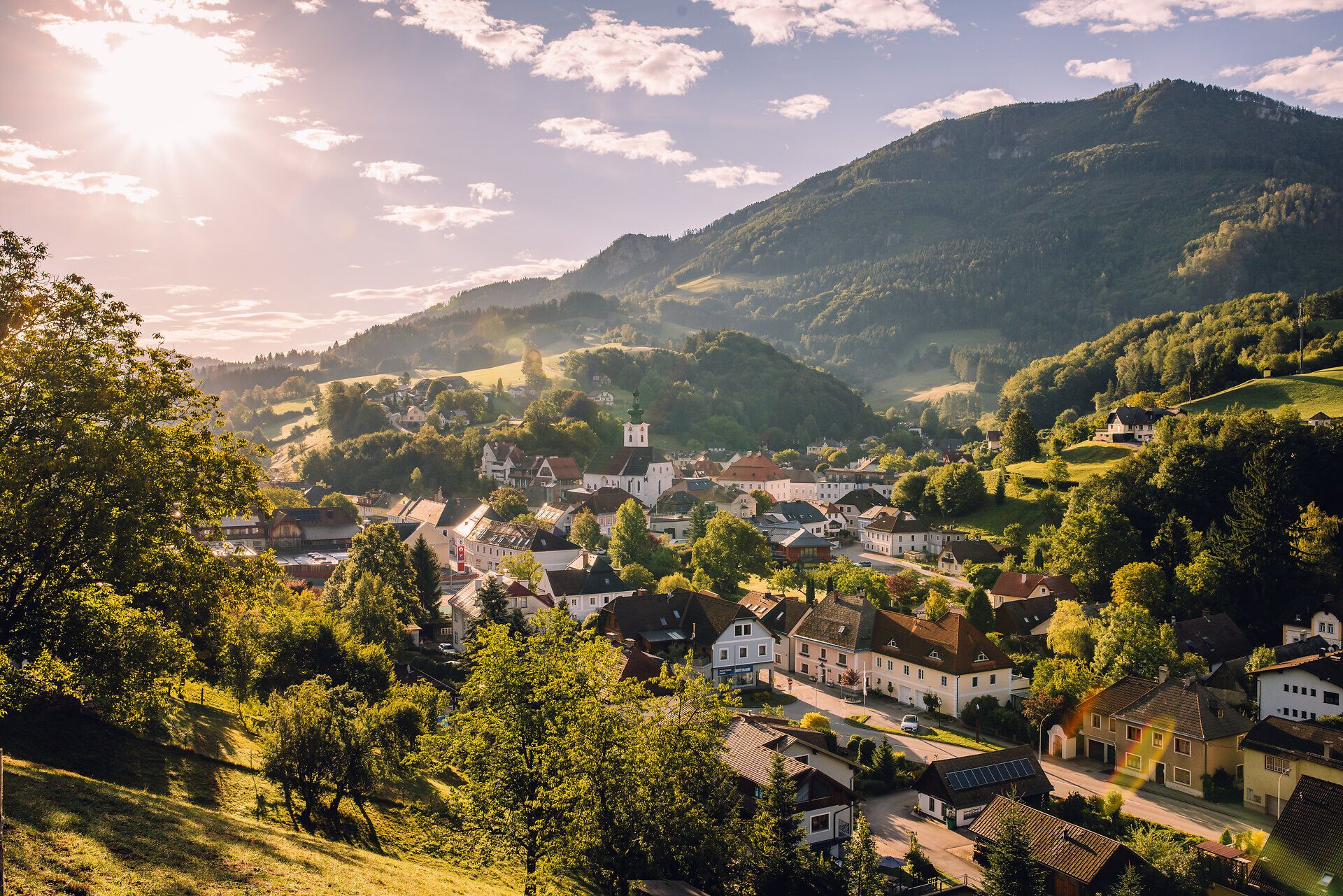 Luftaufnahme von Ybbsitz mit dem Ortszentrum, umgeben von grünen Wiesen und bewaldeten Bergen.