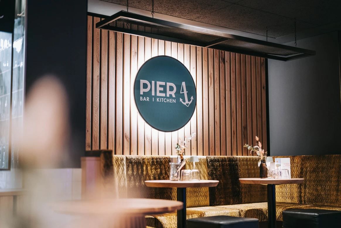 Innenansicht des Restaurants Pier 4 mit Holzwand und Logo.