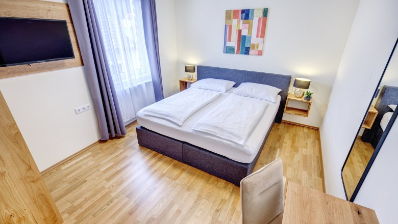 Double room with large window and wooden floor