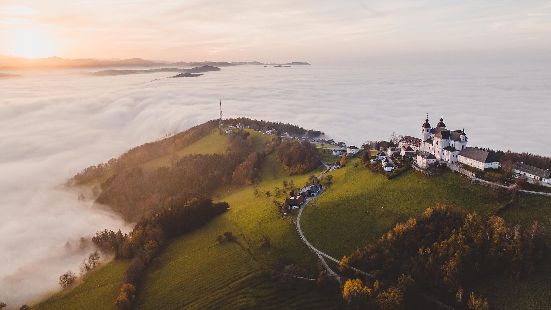 In der sanften Hügellandschaft des Mostviertels breitet sich ein Meer aus Nebel aus, während die warmen Farben des Herbstes die Landschaft in ein malerisches Licht tauchen. Die majestätische Architektur der Klosteranlage thront über den Wolken und lädt zu einem unvergesslichen Besuch ein.