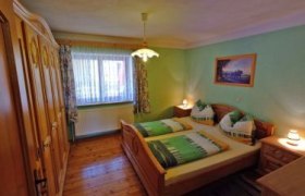 Gemütliches Schlafzimmer mit Doppelbett, Holzmöbeln und grünem Dekor.