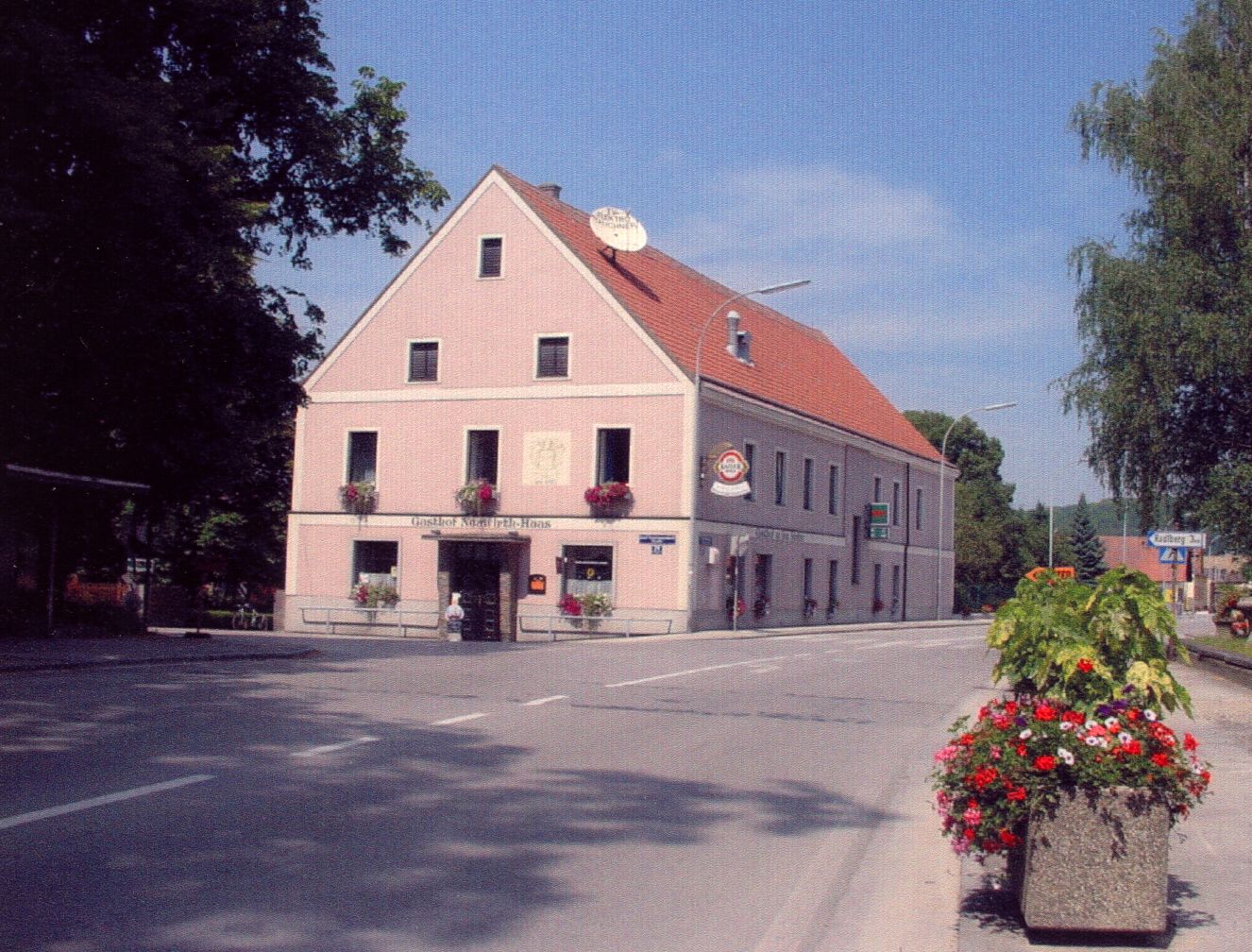 Ein traditionelles Gasthaus an einer Straßenecke mit Blumen geschmückt.