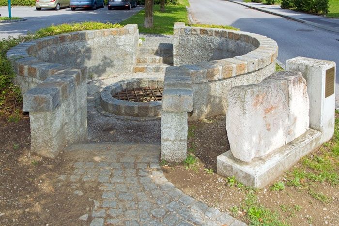 Ein römischer Brunnen in Traismauer mit steinernen Strukturen und einem Gitter über der Öffnung.