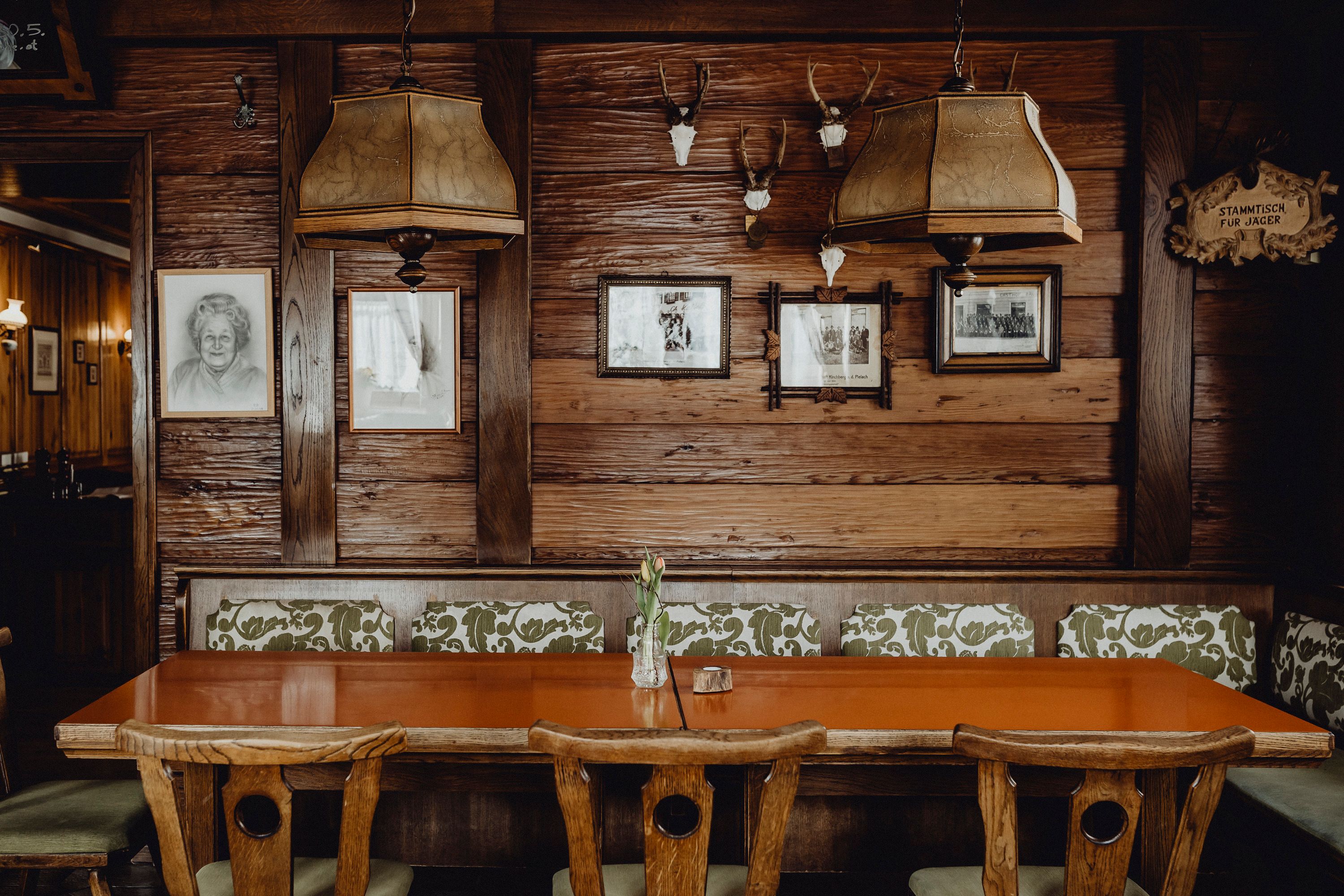 Gemütliches Wirtshaus-Stüberl mit Holztisch, Stühlen und rustikaler Dekoration an der Wand.