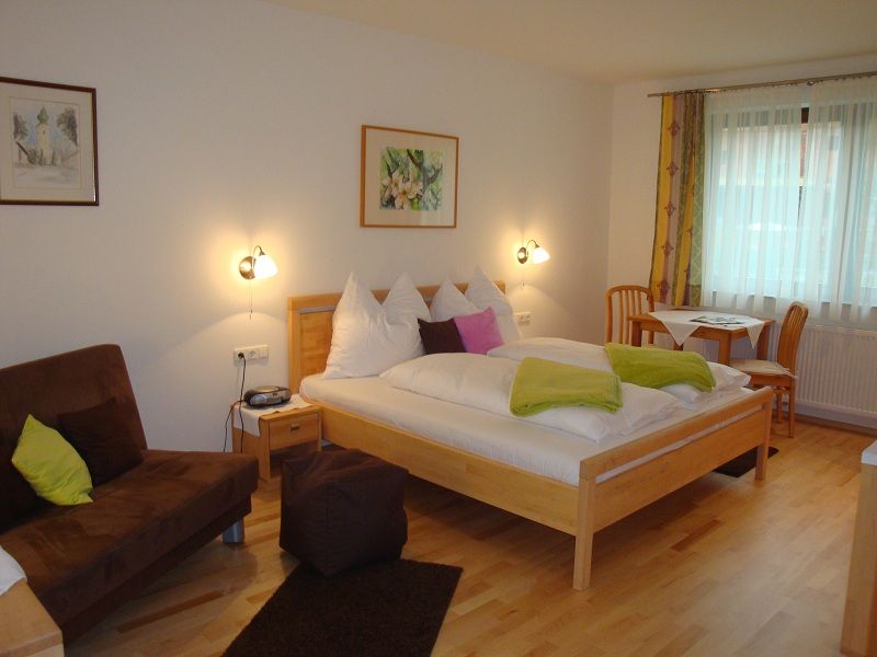 Gemütliches Hotelzimmer mit Doppelbett, Sofa und Esstisch.