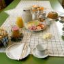 A laid breakfast table with bread rolls, cold cuts, cheese, juice, coffee and cake.