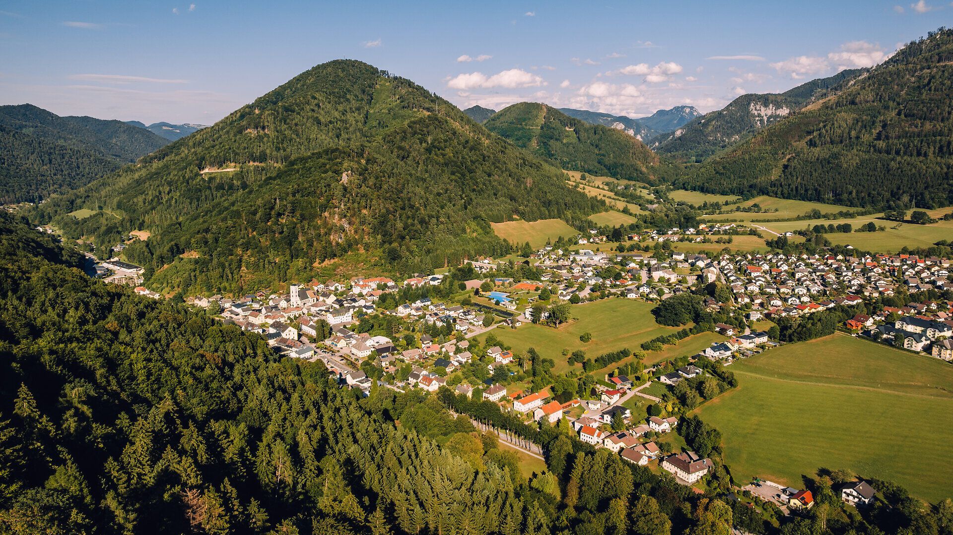 Luftaufnahme von Gaming im Mostviertel mit Ortszentrum, grünen Wiesen und bewaldeten Bergen der Ötscherregion.