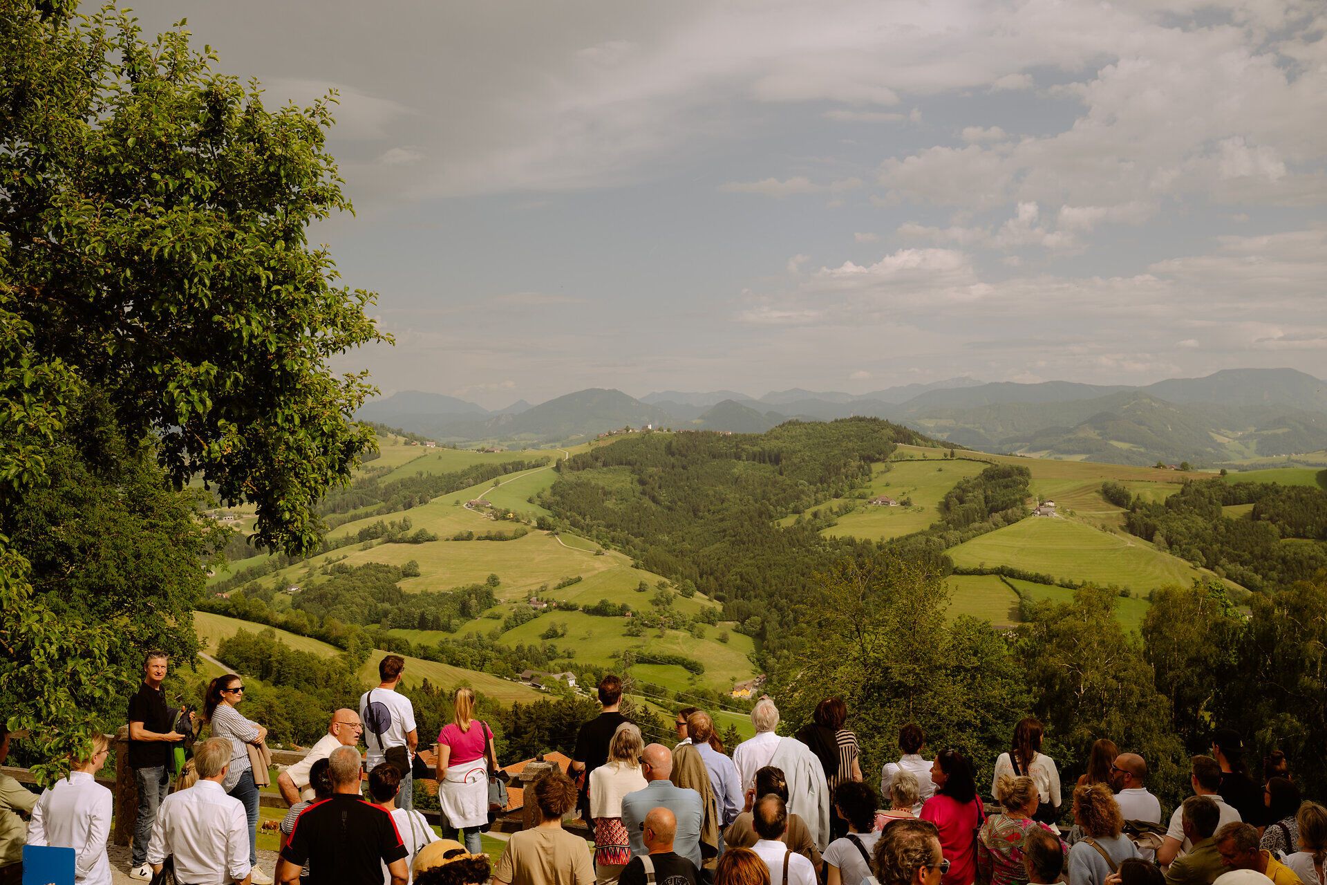 Gruppe von Menschen genießt Ausblick über die Hügellandschaft.