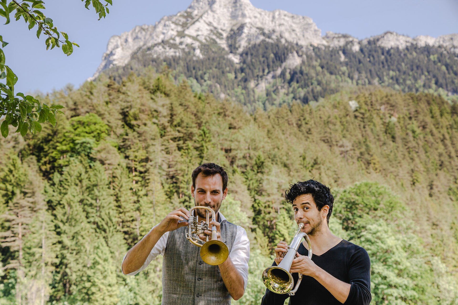 Inmitten der majestätischen Berge, umgeben von üppigem Grün, erklingen fröhliche Trompetenklänge. Zwei Musiker bringen mit ihrer Leidenschaft und Energie die alpine Sommeratmosphäre zum Leben und laden dazu ein, die Schönheit der Natur zu genießen.