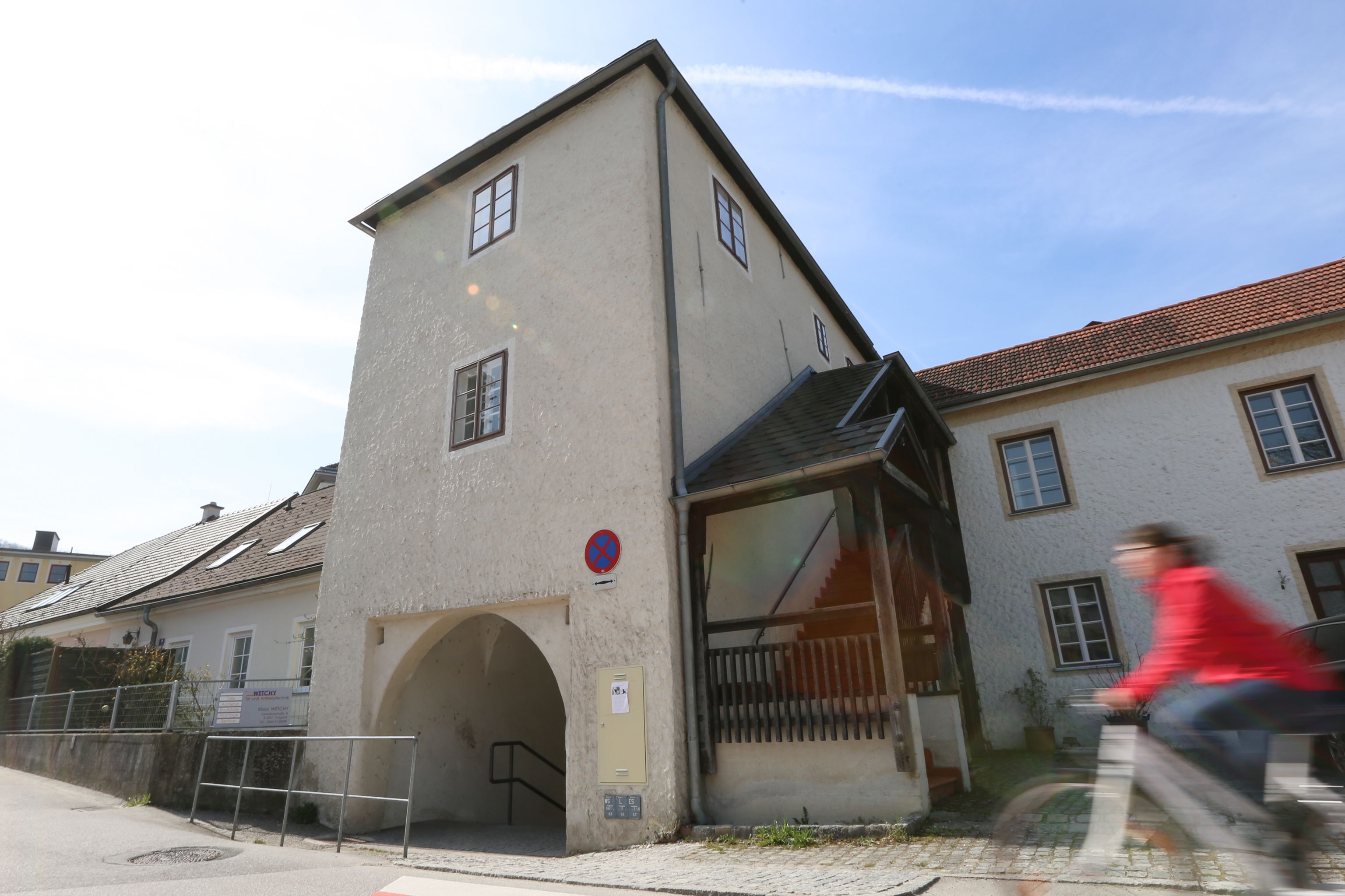 Ein historisches Gebäude mit einem Torbogen und einer Person auf einem Fahrrad im Vordergrund.