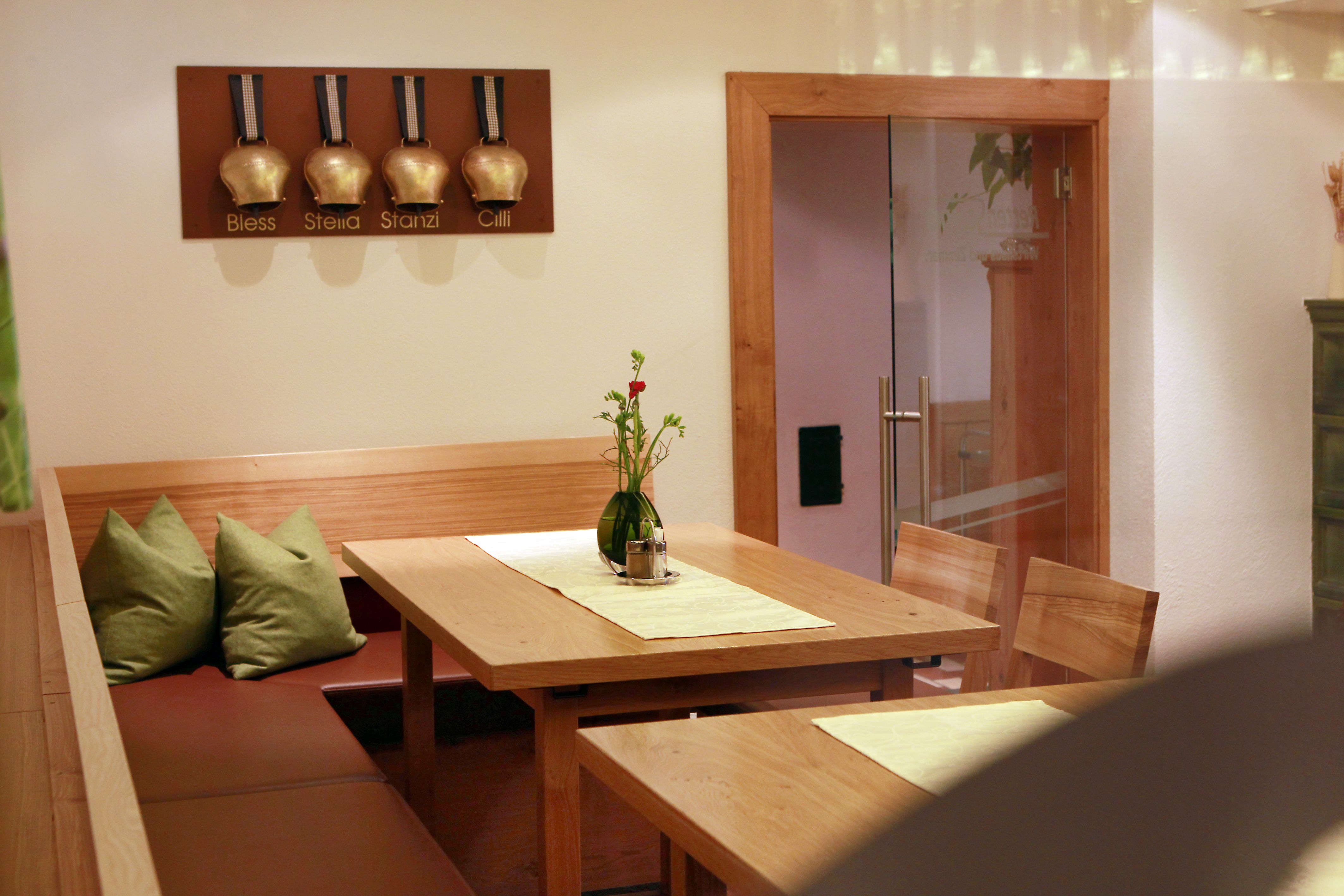 Gemütliche Sitzecke in einem Restaurant mit Holztisch und grünen Kissen.