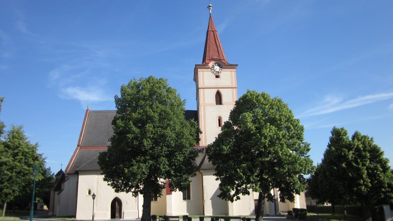 Pfarrkirche Pyhra mit Turm und Bäumen im Vordergrund.