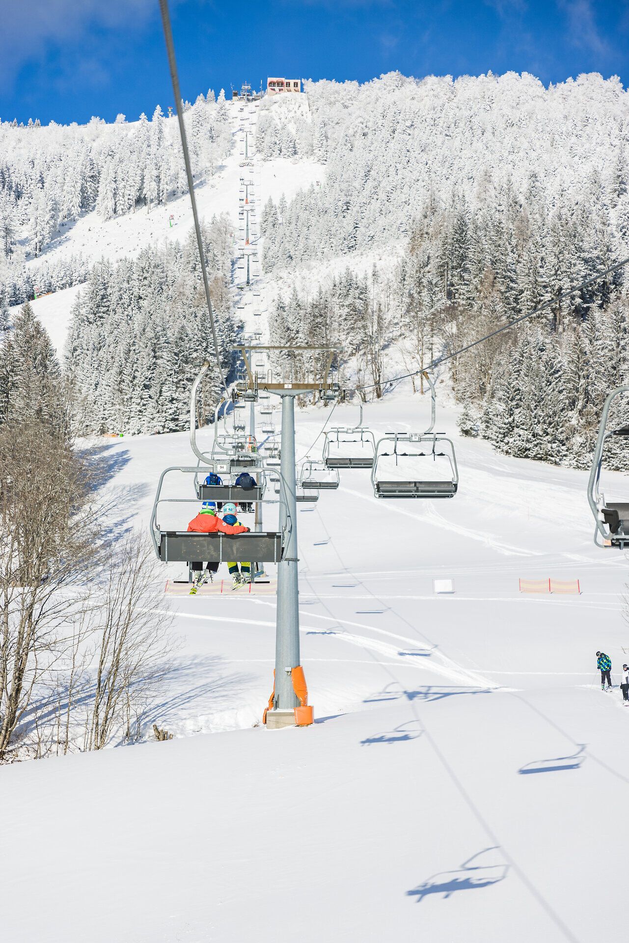 Die schneebedeckten Hänge laden zu einem unvergesslichen Skitag ein, während der Sessellift gemächlich die Gäste zu neuen Höhen bringt. Umgeben von majestätischen, verschneiten Bäumen und strahlend blauem Himmel, erleben Wintersportler hier pure Freude und Freiheit.
