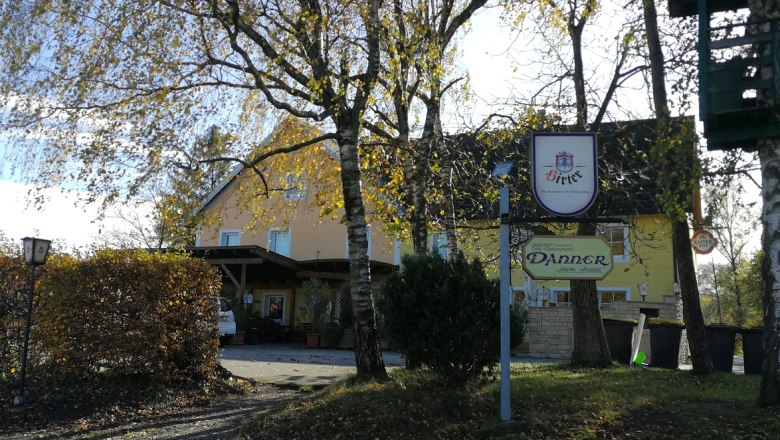Gasthaus Danner mit Bäumen im Vordergrund und einem Schild.