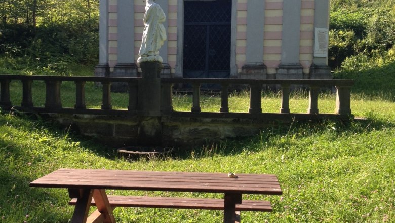 Picnic table in front of a small chapel in the countryside.