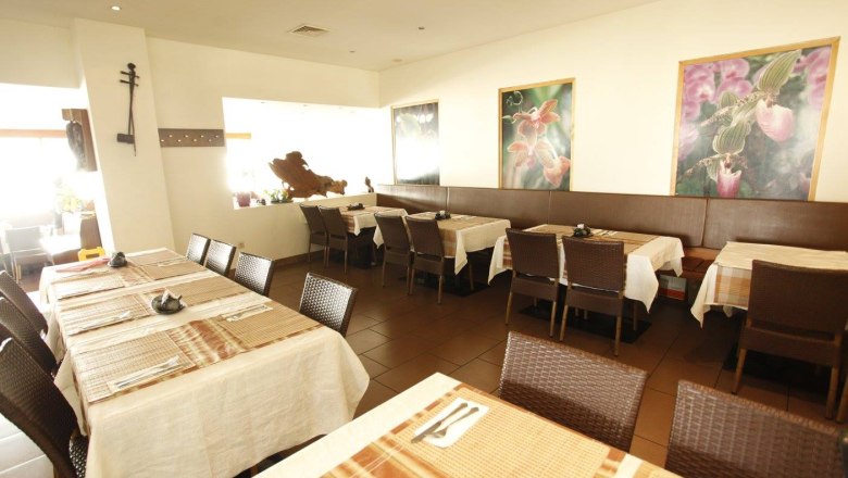 Innenansicht eines Restaurants mit gedeckten Tischen und Blumenbildern an der Wand.