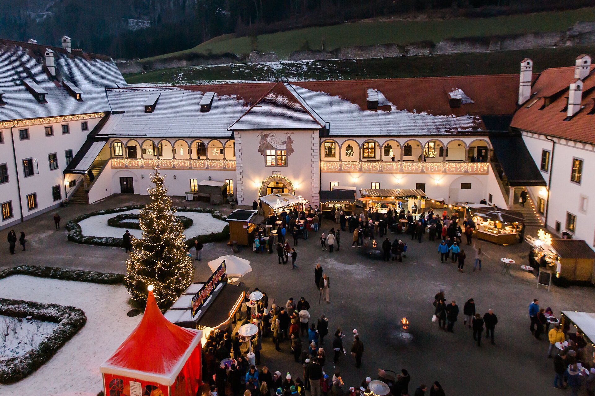 Der festlich geschmückte Adventmarkt erstrahlt in warmem Licht und zieht Besucher mit seinem einladenden Ambiente an. Stände mit handgefertigten Produkten und köstlichen Leckereien laden zum Verweilen ein, während der Duft von Glühwein und frisch gebackenem Gebäck die Luft erfüllt.