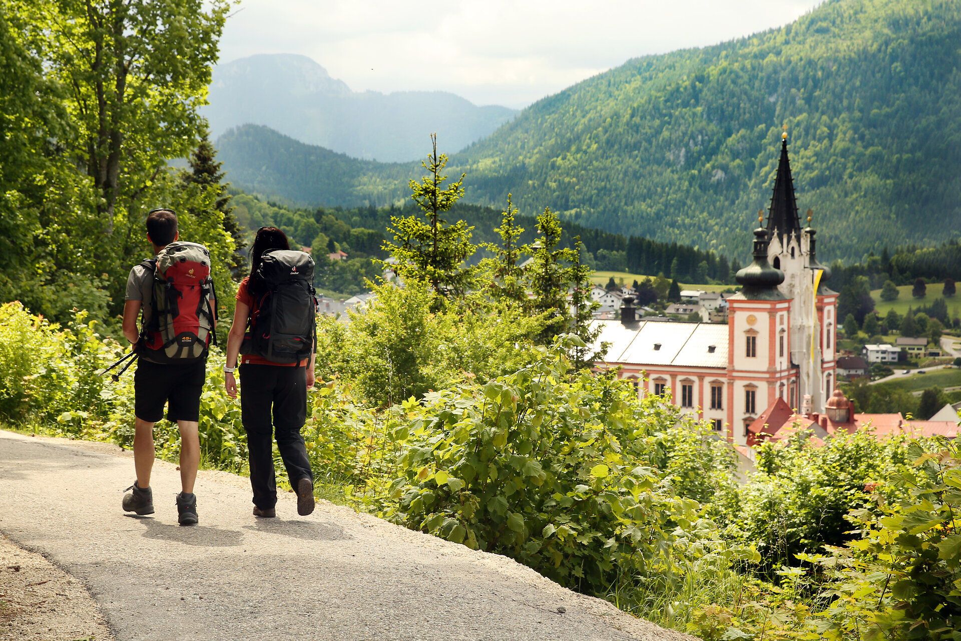 Die sanften Hügel und die majestätische Basilika im Hintergrund laden zu einer besinnlichen Pilgerwanderung ein. Umgeben von üppigem Grün und der frischen Bergluft, erleben Wanderer hier eine harmonische Verbindung von Natur und Spiritualität.