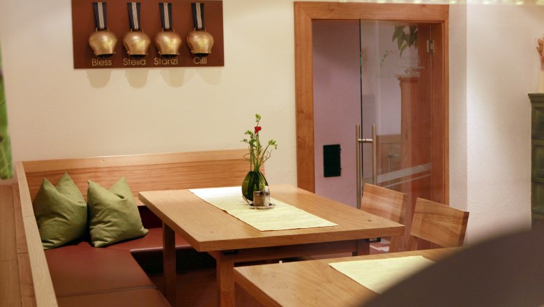 Gemütliche Sitzecke in einem Restaurant mit Holztisch und grünen Kissen.