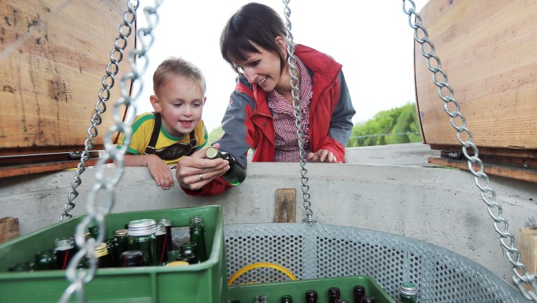 Ein Kind und eine Frau betrachten Flaschen in einem Brunnen.
