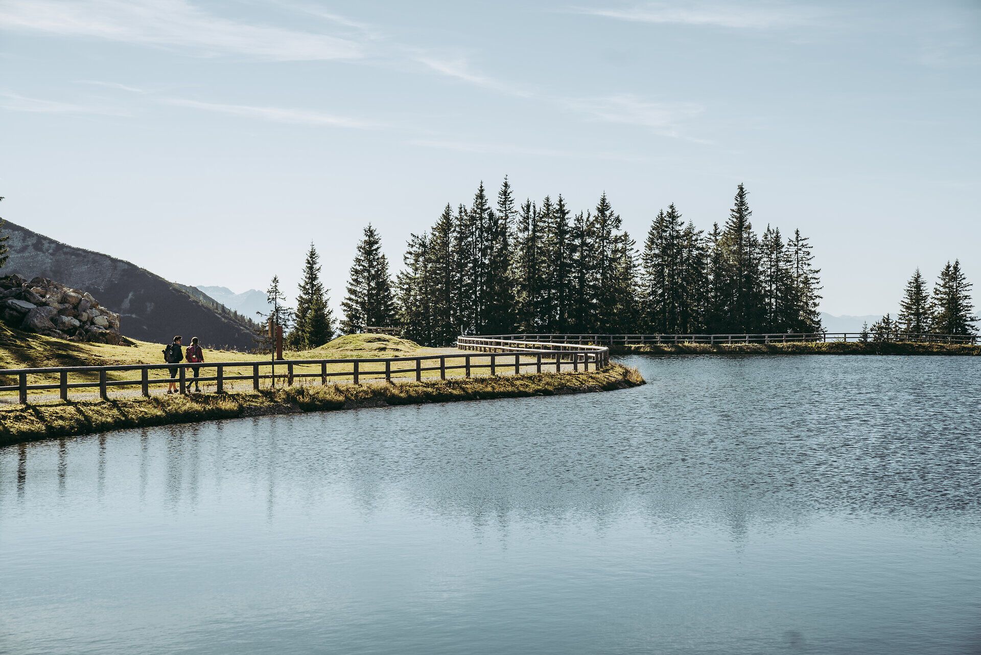 Ein malerischer Bergsee spiegelt die umliegenden Nadelbäume wider und lädt Wanderer zu einer wohlverdienten Pause ein. Die sanften Hügel und die klare Luft schaffen eine friedliche Atmosphäre, die zum Verweilen einlädt. Hier, inmitten der Ybbstaler Alpen, wird der Sommer in den Bergen zum unvergesslichen Erlebnis.