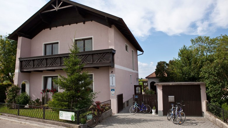 Street view of the house with well-kept front garden and driveway with garage.