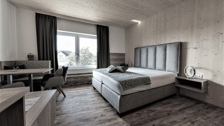 Modern eingerichtetes Hotelzimmer mit Doppelbett, Sitzbereich und großem Fenster.