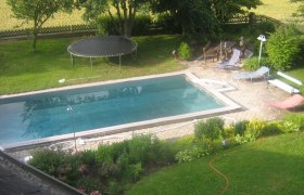Garten mit Pool, Trampolin und Liegestühlen.