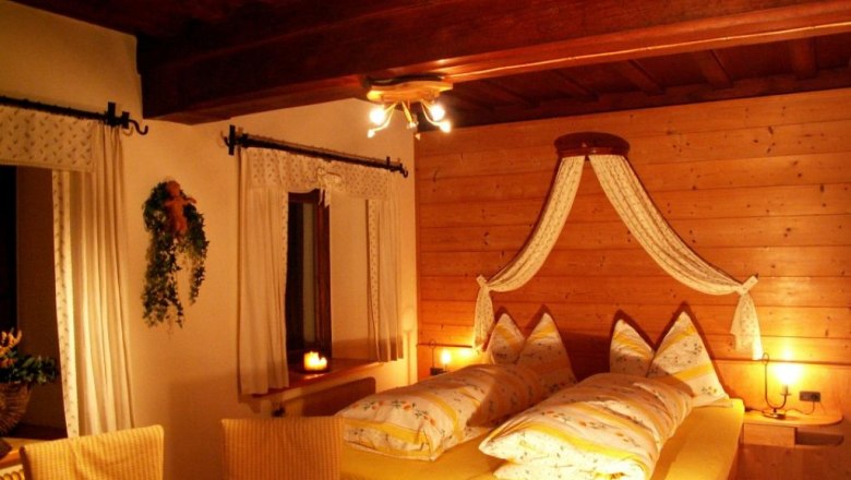 Gemütliches Schlafzimmer mit Holzwänden und gelber Bettwäsche.