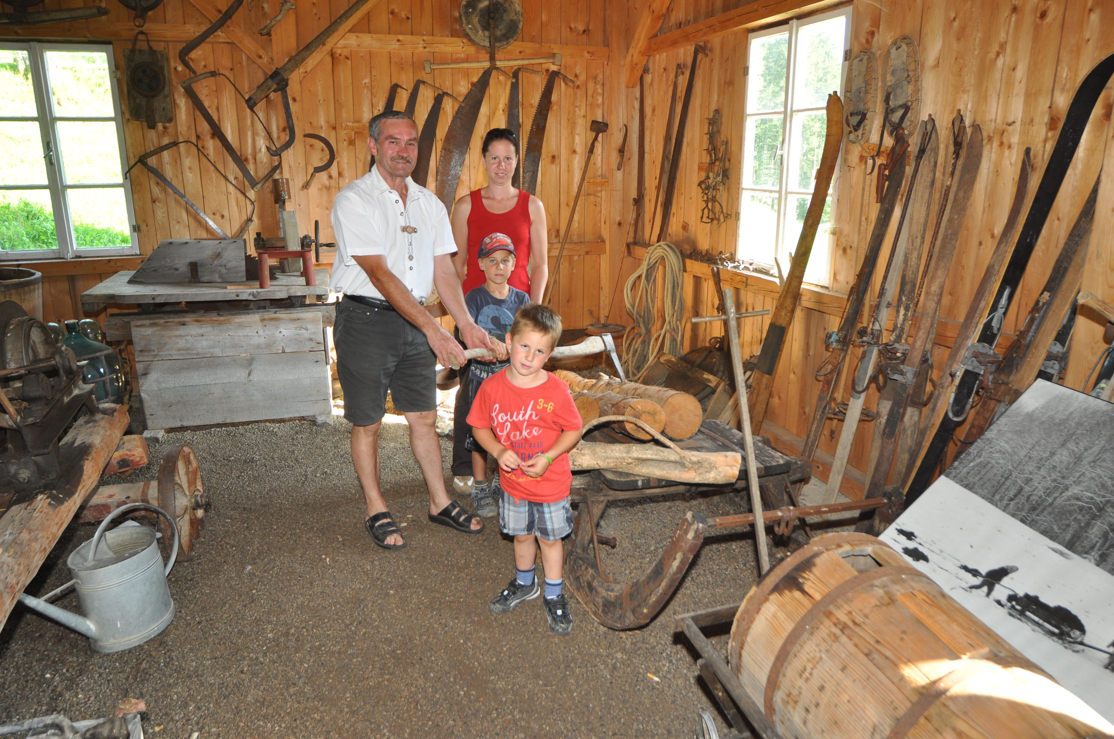 Eine Familie in einem rustikalen Raum mit alten landwirtschaftlichen Werkzeugen und Geräten.