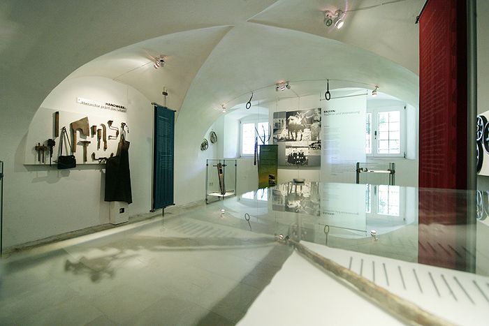 Innenansicht eines Museums mit Werkzeugen und historischen Fotos.