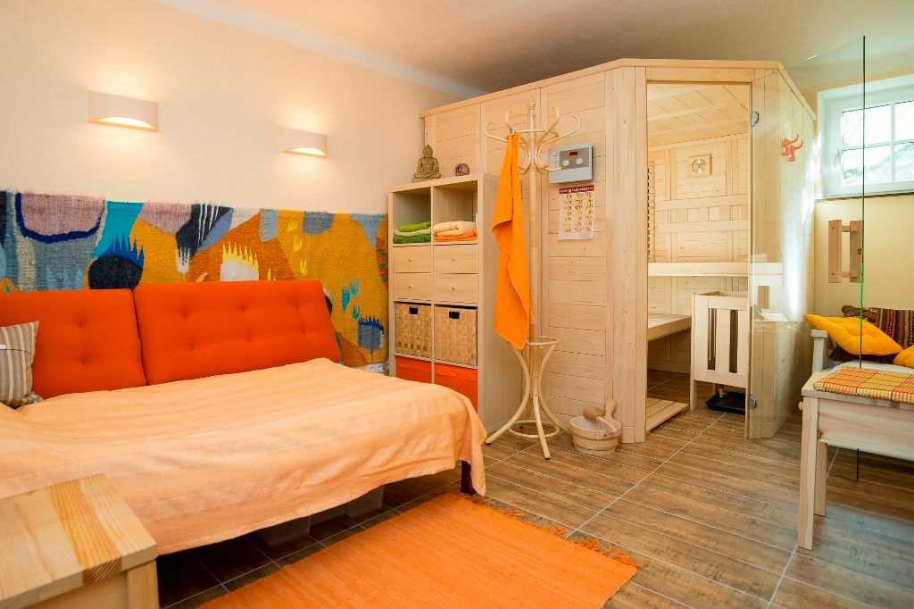 Gemütliches Wohnzimmer mit Sauna, Sofa und bunter Wanddekoration.