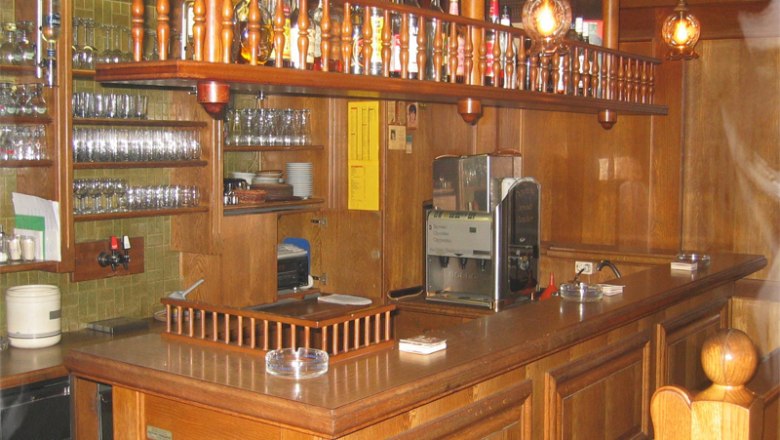 Innenansicht einer traditionellen Bar mit Holzeinrichtung und Gl&auml;sern.