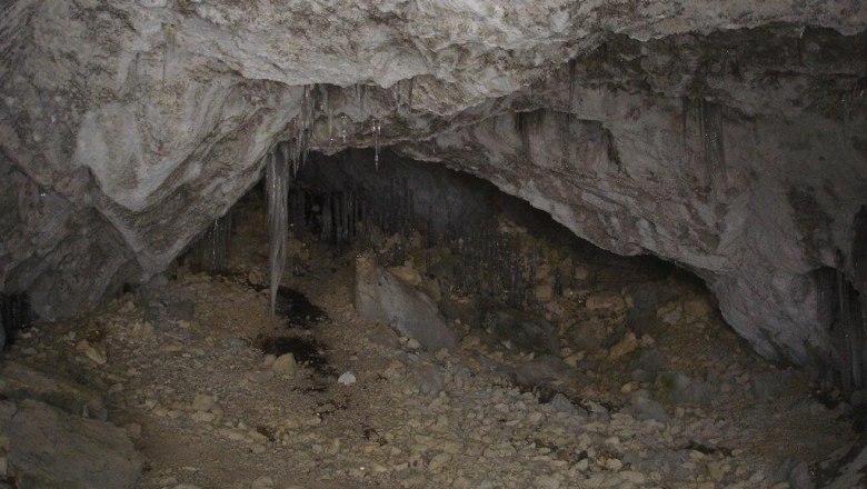 Innenansicht einer trockenen Höhle mit Stalaktiten und steinigem Boden.