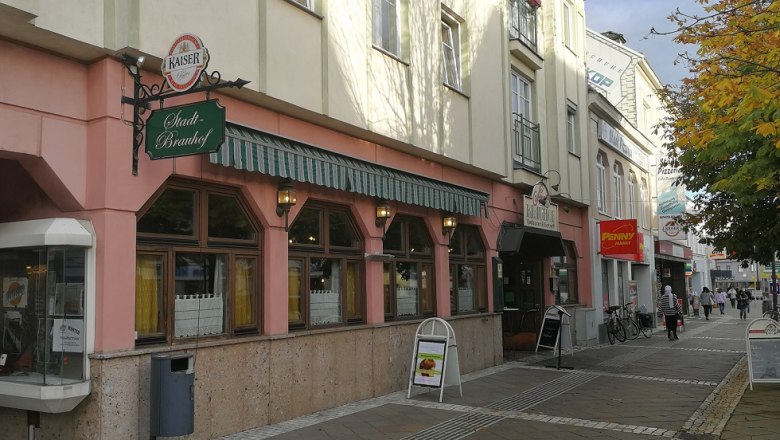 Straßenszene mit dem Stadtbrauhof Amstetten und umliegenden Geschäften.