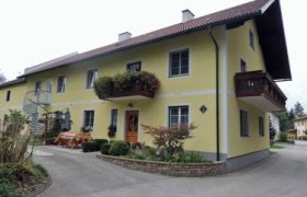 Gelbes zweistöckiges Haus mit Balkon und Garten.