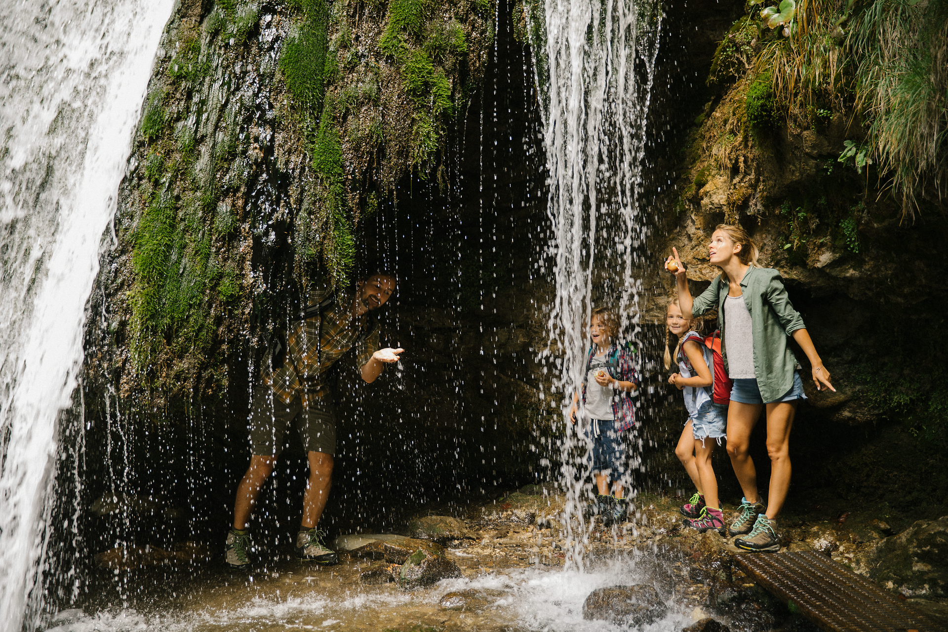 Ein erfrischender Wasserfall umrahmt von üppigem Grün lädt Familien zu einem unvergesslichen Naturerlebnis ein. Kinder lachen und spielen im spritzenden Wasser, während die Erwachsenen die friedliche Atmosphäre genießen. Hier in der Natur wird das Wandern zum Abenteuer für Groß und Klein.