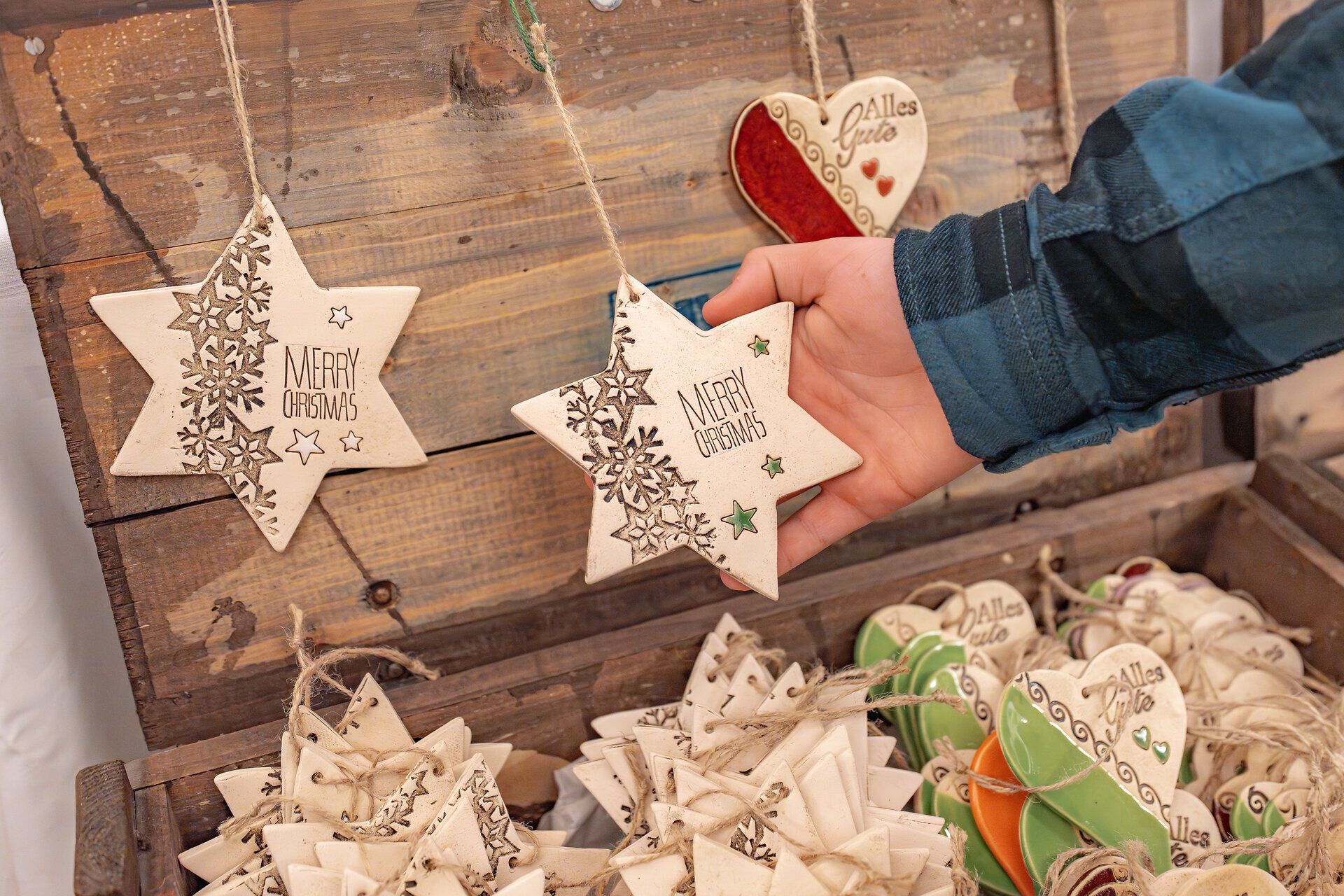 Besuchende des Adventmarkts betrachten handgefertigte Waren. 