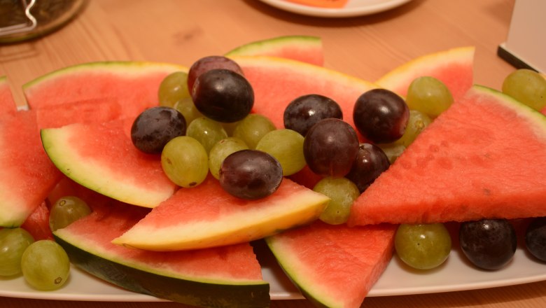 Ein Teller mit Wassermelonenstücken und Trauben.