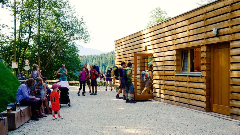 People in front of a modern wooden building in a forest environment.