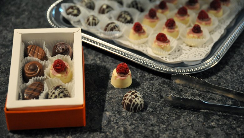 A box of chocolates and a tray of chocolates on a table.