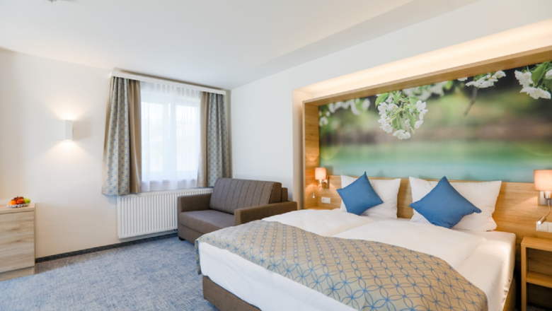 Modern hotel room with double bed, sofa and large mural with floral motif.